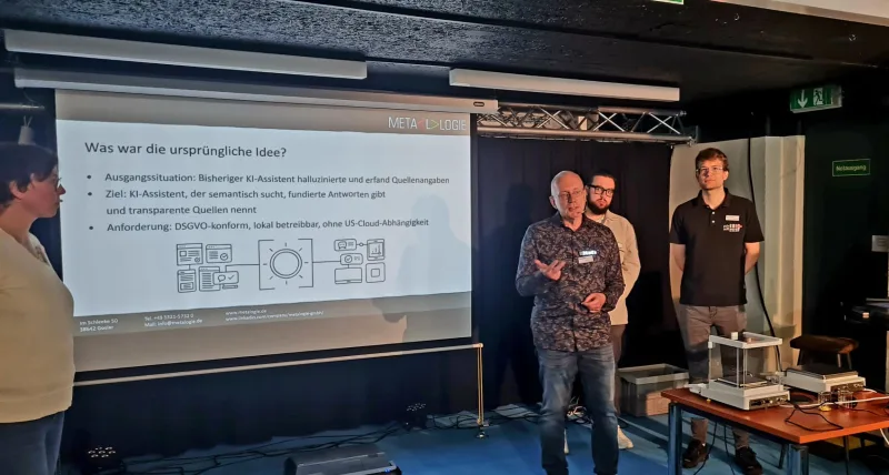 Metalogie-Forum 2026 in Goslar: Stefan Weimar, Leon Wolf und Domenik Häring präsentieren das KI-Pilotprojekt Marie vor der Vortragsfolie ‚Was war die ursprüngliche Idee?‘